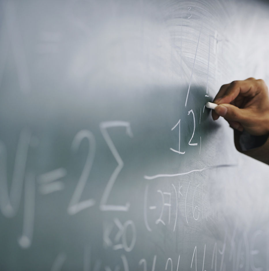 Teacher Writing a Formula on a Blackboar